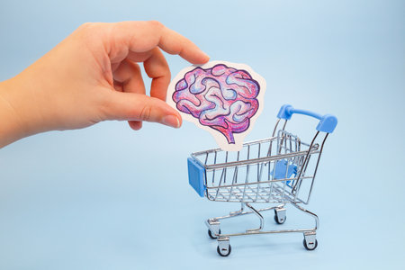 Hand lowers painted brain into shopping cart. Concept of buying ideas and smart thoughts. Brain drain abroad. Symbol of departure of educated people.の写真素材