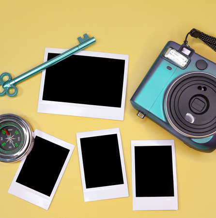 White picture frames with empty place for image lie on beige background with instant camera. green...