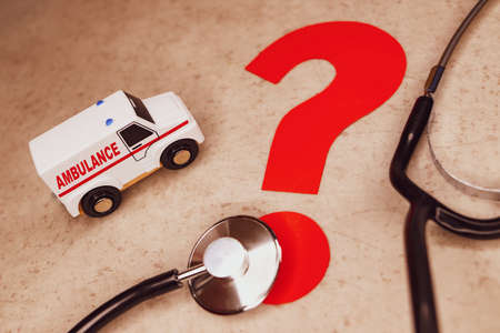 white ambulance on gray background next to red question mark and stethoscope. Quick diagnosis of patient.の写真素材