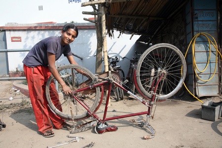 BARUIPUR, INDIA - JANUARY 13: Mechanic in the workshop repair the tire on a bicycle. The bicycle is in India, one of the main means of transport., Baruipur, West Bengal on January 13, 2009.のeditorial素材