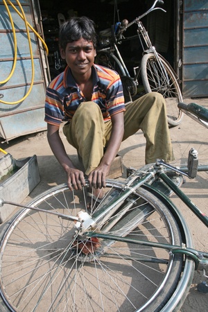 BARUIPUR, INDIA - JANUARY 13: Mechanic in the workshop repair the tire on a bicycle. The bicycle is in India, one of the main means of transport., Baruipur, West Bengal on January 13, 2009.のeditorial素材