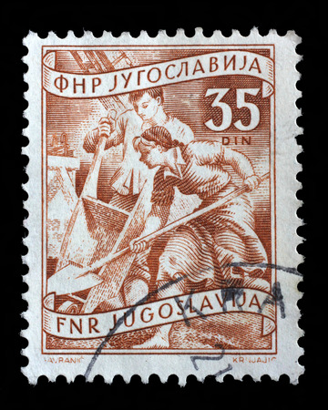 A stamp printed in Yugoslavia shows working at a construction site, domestic economy Series, stamp for surcharges, circa 1952のeditorial素材