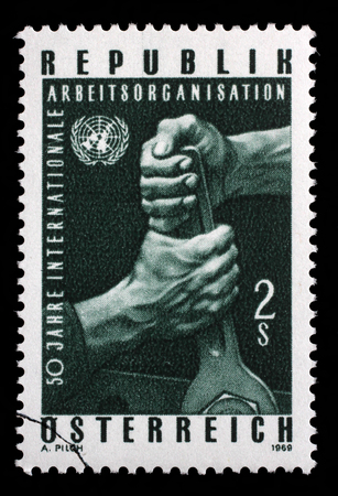Stamp printed in the Austria shows Hands Holding Wrench, and UN Emblem, 50th Anniversary of ILO, circa 1969のeditorial素材