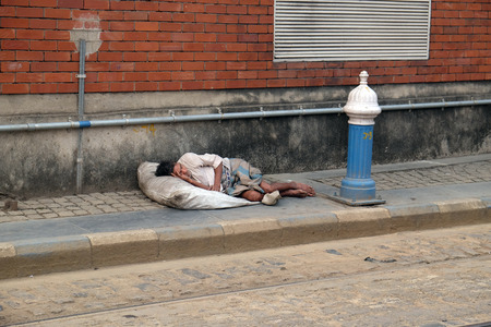 A homeless man lies asleep on the pavement outside the busy train station in Kolkata, India on February 10, 2016.のeditorial素材