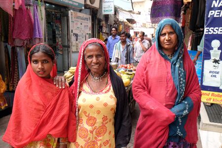 Three Indian women with colorful veil and, sari and a nose jewellery posing on the street of Pushkar, Rajasthan, Indiaのeditorial素材