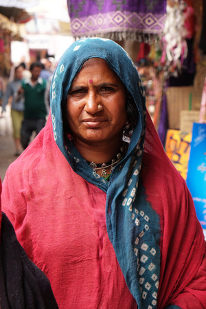 Indian woman with colorful veil and, sari and a nose jewellery posing on the street of Pushkar, Rajasthan, India on February 18, 2016.のeditorial素材