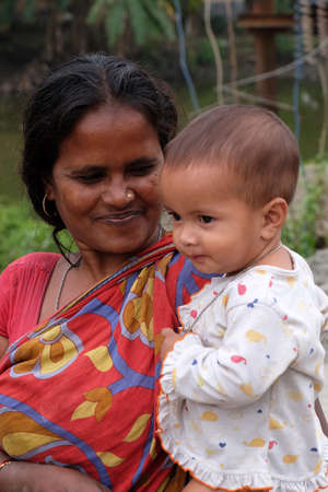Mother with child during an outdoor Mass in Mitrapur village, West Bengal, Indiaのeditorial素材