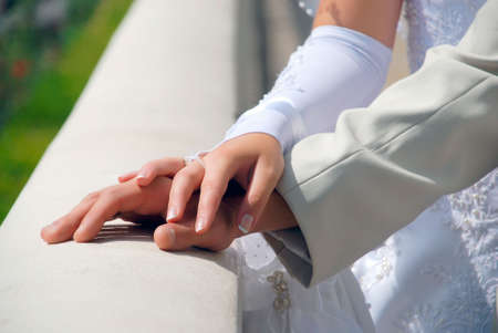 Hands behind the newlyweds on the fence in the parkの写真素材