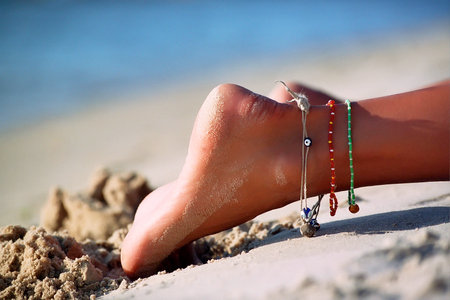 Foot with Baubles girl lying on the sandの写真素材