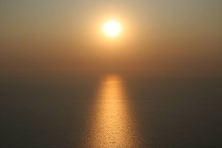 The sun is setting into the sea. On the water visible to the solar path. background imageの写真素材