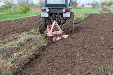 Tractor with plow fastened spring plowed field. Spring care of the farmer, the opening of the season of spring agricultural works.の写真素材