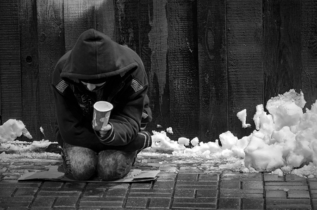 The poor man begs alms on a wet, cold floor in the middle of winter.の写真素材