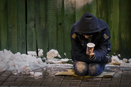 The poor man begs alms on a wet, cold floor in the middle of winter.の写真素材