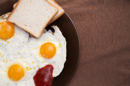 English breakfast, fried eggs with toast on an old textured table.の写真素材