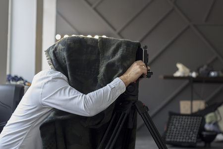 photographer hiding under a black cape with retro camera.の写真素材
