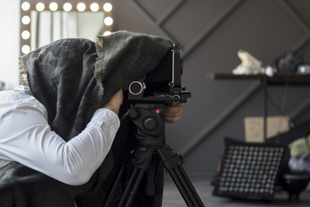 photographer hiding under a black cape with retro camera.の写真素材