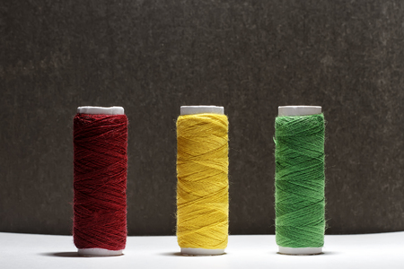Set of pastel colors thread for sewing on a black background. Set of threads on bobbins retro style. Vintage accessories for sewing on the table. Multicolor spools of thread isolated.の写真素材