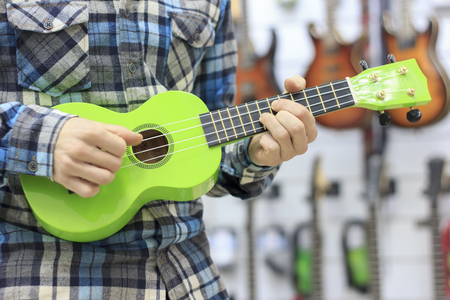 Portrait of a bearded hipster male in red hat playing on ukuleleの写真素材