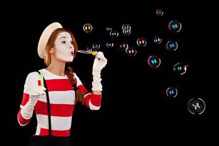 Portrait of the female MIM comedian blows soap balls, isolated on black background の写真素材