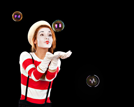 Portrait of the female MIM comedian catches bubbles, isolated on black backgroundの写真素材