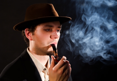 A young man smoking a pipe on a black backgroundの写真素材