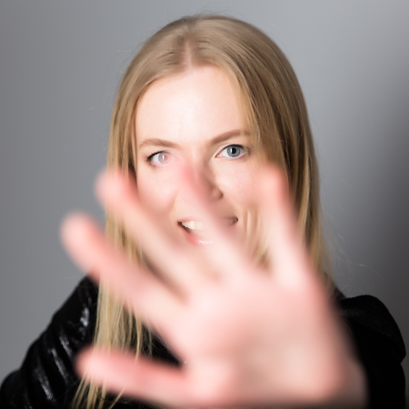 portrait of a young beautiful blond woman with evening make-up in a black shiny dress near a gray wall.の写真素材