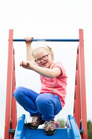 healthy childhood in the city - portrait of a cheerful active girl on a playgroundの写真素材