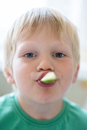 healthy food for children - portrait of a small boy with a fresh cucumber in his mouthの写真素材