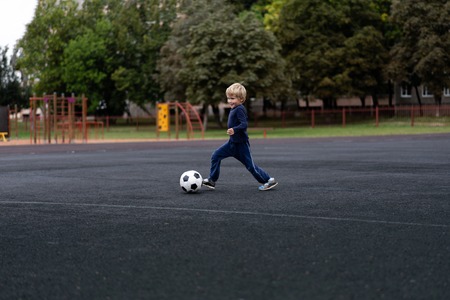 active lifestyle in a modern city - little boy playing with a soccer ball at the stadiumの写真素材