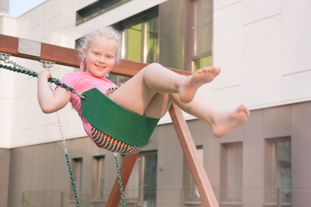 life of children in a modern city - the girl is having fun on the playground near the houseの写真素材