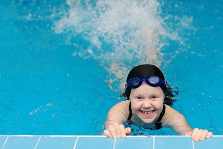 swimming lessons for children in the pool - beautiful fair-skinned girl swims in the waterの写真素材