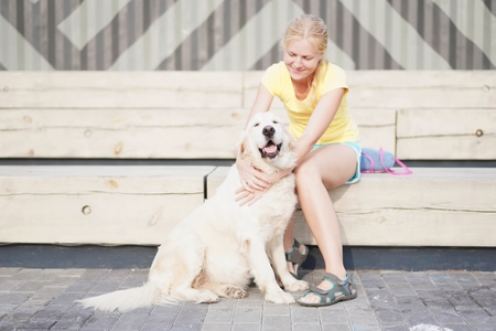 love for pets - a young blonde woman resting with her dog on the streetの写真素材