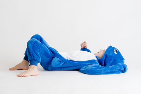 cheerful little boy posing on a white background in pajamas, blue shark costumeの写真素材