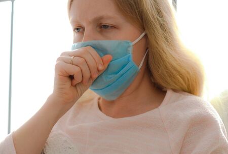 quarantine for coronavirus epidemic. An infected masked woman is resting in bed in the bedroom.の写真素材