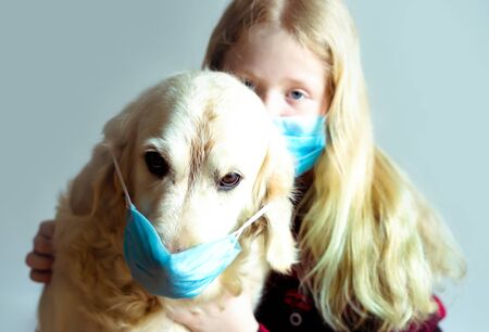 funny photo - quarantined due to an epidemic of coronavirus. portrait of a masked dog and girl on a gray background.の写真素材