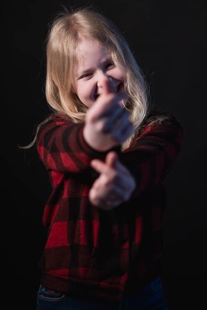 happy schoolgirl posing in studio on a black background - shows hands signs heartsの写真素材