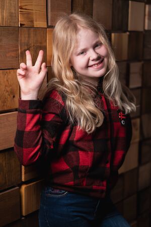 portrait of a blonde teen girl near a decorative wall of wooden blocks in studioの写真素材