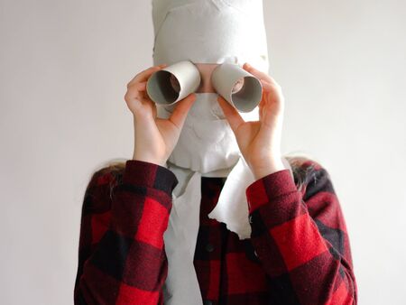 funny photo - quarantined due to an epidemic of coronavirus. girl in a mask from toilet paper posing on a gray background.の写真素材