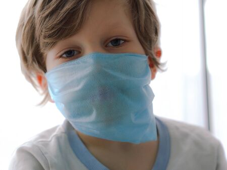 protection against coronavirus. little boy puts a mask on her face.の写真素材