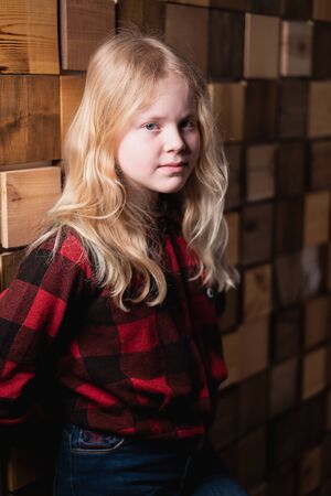 portrait of a blonde teen girl near a decorative wall of wooden blocks in studioの写真素材