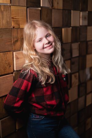 portrait of a blonde teen girl near a decorative wall of wooden blocks in studioの写真素材