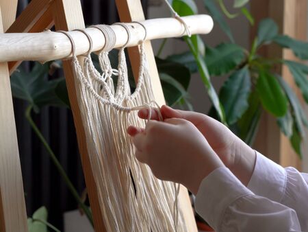 stay at home. work during the quarantine - a girl in the living room mural weaving of the ropes in the macrame techniqueの写真素材
