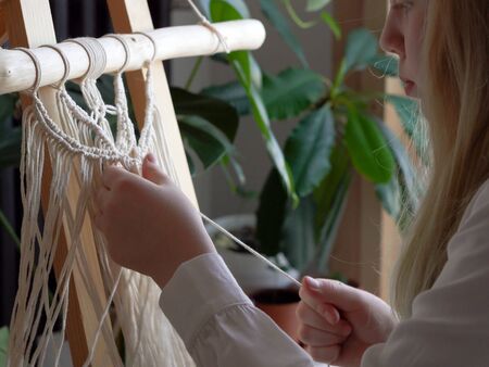 stay at home. work during the quarantine - a girl in the living room mural weaving of the ropes in the macrame techniqueの写真素材