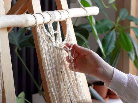 stay at home. work during the quarantine - a girl in the living room mural weaving of the ropes in the macrame techniqueの写真素材