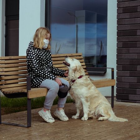 coronavirus pandemic in the city. girl walking a golden retriever dog along empty streets