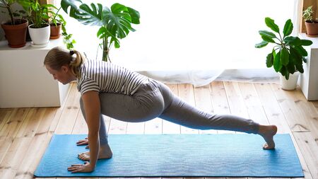 stay at home. masked woman doing yoga in the living room during quarantineの写真素材