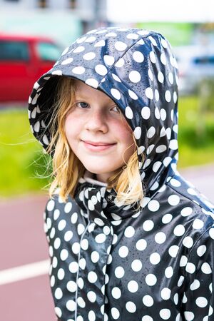 portrait of a beautiful teenager girl in a raincoat in the rain.の写真素材