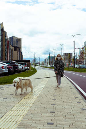 coronavirus pandemic in the city. girl walking a golden retriever dog along empty streetsの写真素材