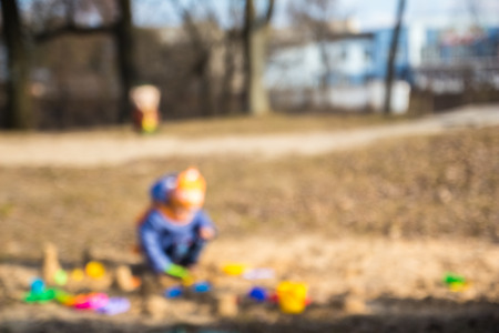 Small lone child playing in the sandbox. The blurringの写真素材