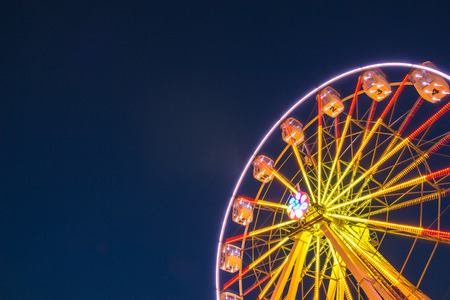 Part of ferris wheel against a blue sky background with lights night lightingの写真素材